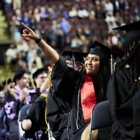 A student points to the crowd during the 187th Commencement ceremony at the Cross Insurance Arena in Portland